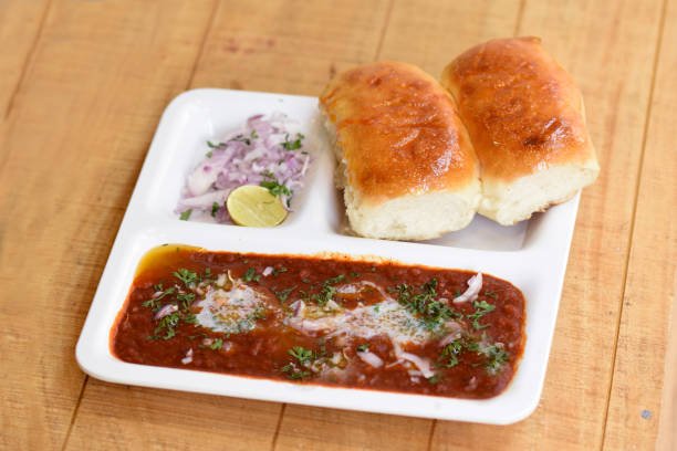 Indian delicious Pav Bhaji with onion and coriander spread on top of curry wheat bread Pav Bhaji fast food dish from India.